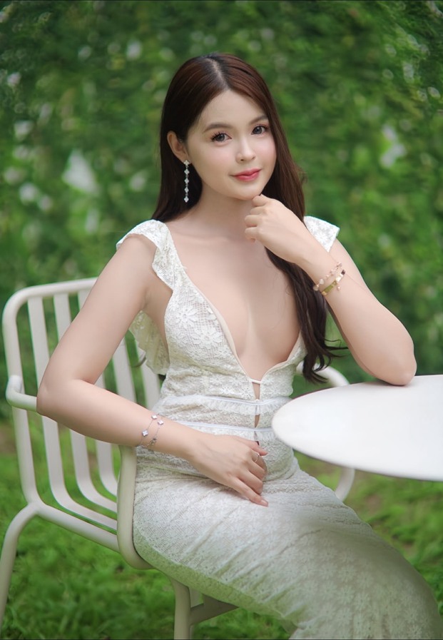 Khai Muchita นั่งถ่ายแบบในชุดขาวริมโต๊ะกลางแจ้ง