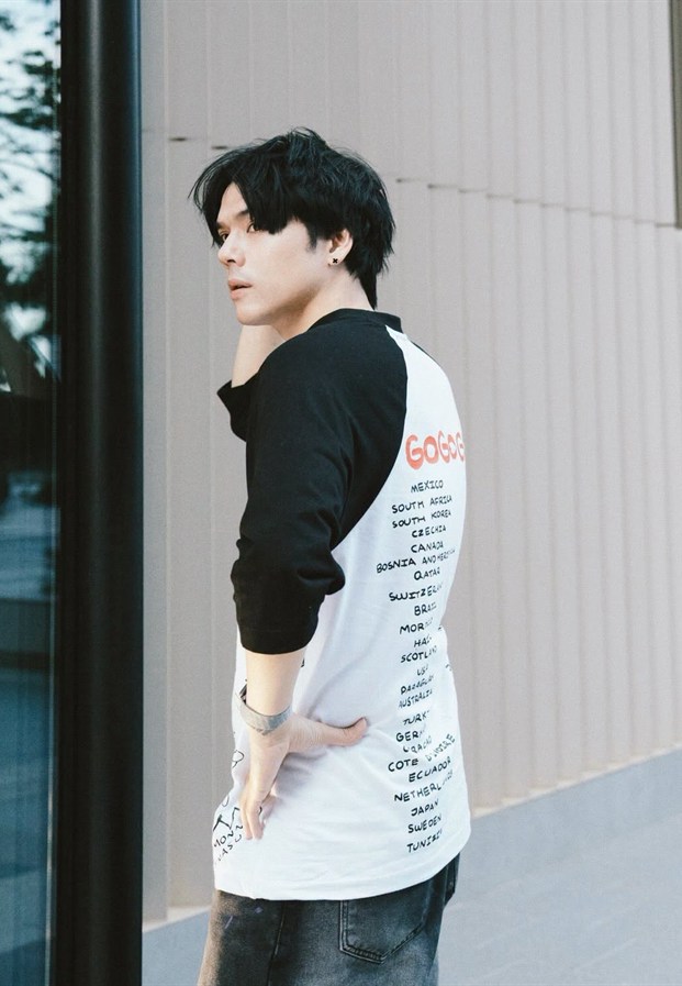Nicky หันข้างโชว์ลายหลังเสื้อริมผนังอาคาร