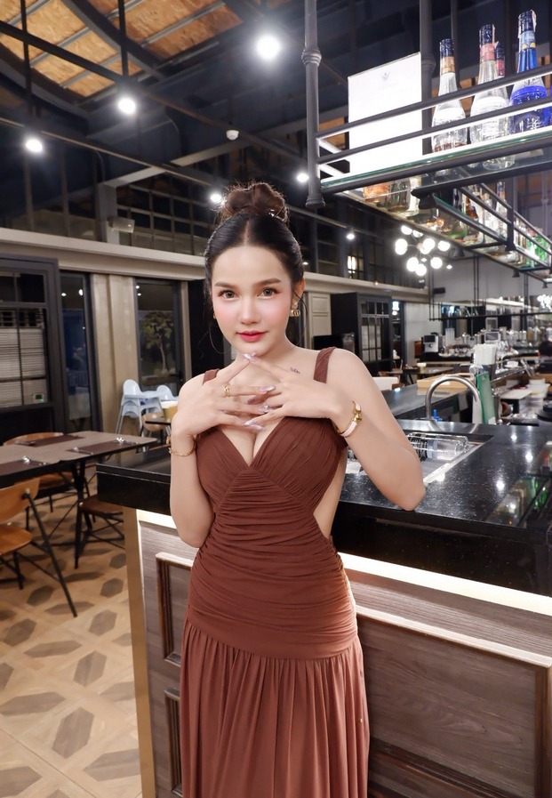 Eye Ramida ในชุดเดรสสีน้ำตาลยืนในร้านคาเฟ่