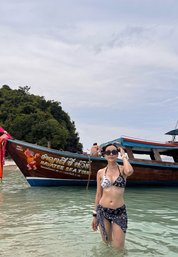 รติญา พิชญ์ศราพงศ์ ในชุดว่ายน้ำยืนริมเรือหางยาว