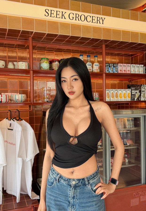 Panisara Thodsaphob ในเสื้อคล้องคอสีดำยืนหน้าชั้นสินค้า